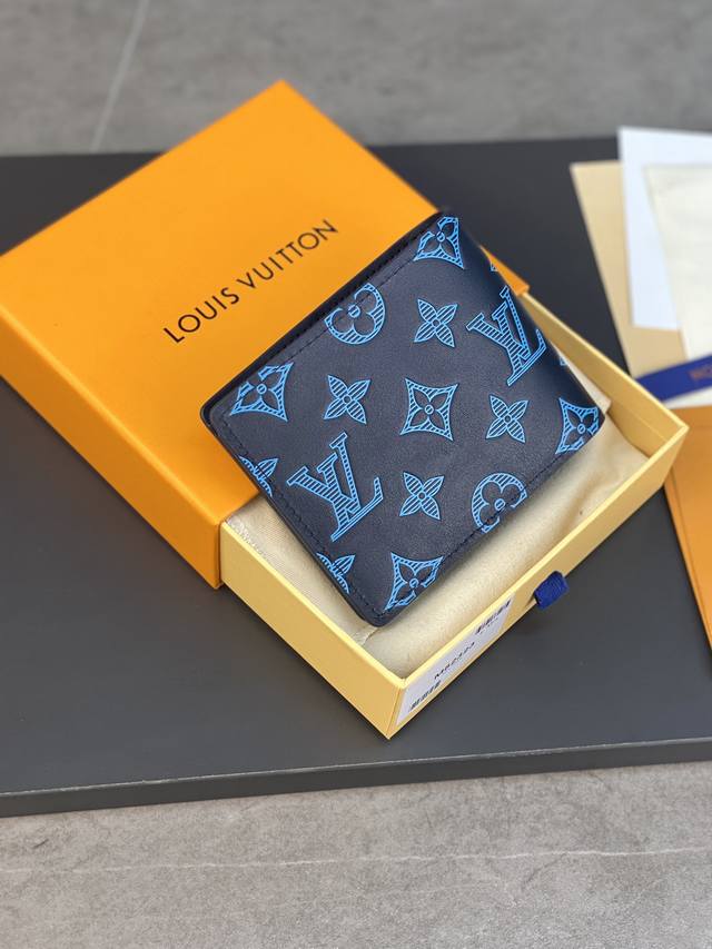 M82323蓝色 本款 Multiple 钱夹选用柔滑牛皮革 以印花和压印工艺再现 Georges Vuitton 于 1896 年绘制的 Monogram 图